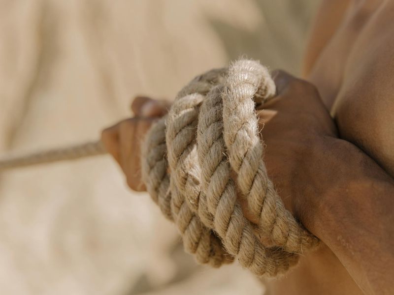 Close-up of a man's hands gripping a bar, showing muscle tension.